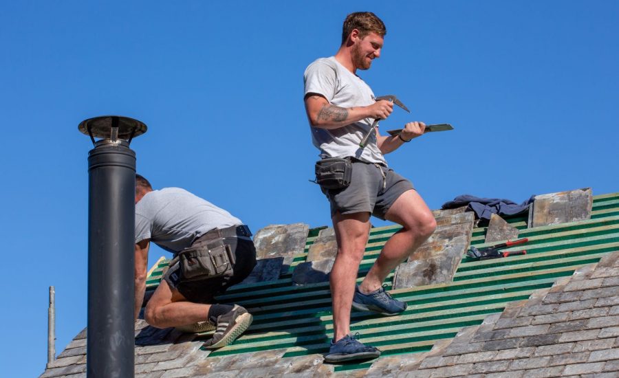 A roofer standing on a roof laying tiles.